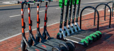 Photo of two brands of e-scooters lined up on a brick sidewalk